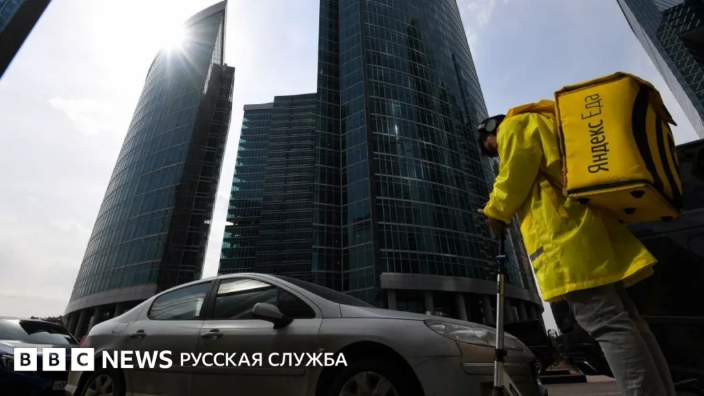 Курьер с красным рюкзаком на фоне небоскребов. Источник фото: bbc.com